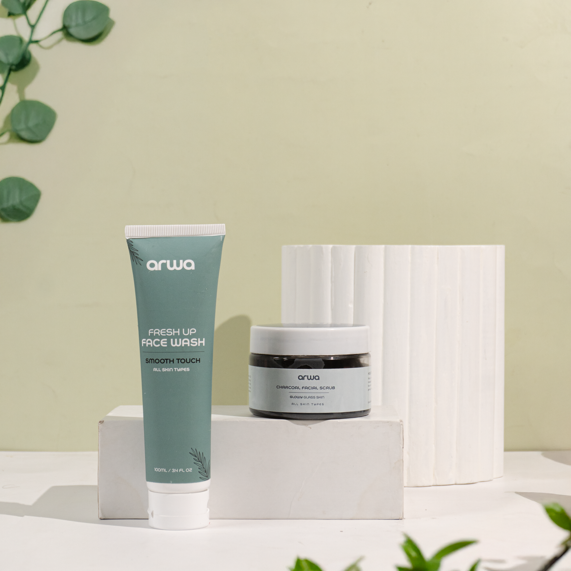 Arwa skincare products including face wash, and scrub on a neutral background with greenery.